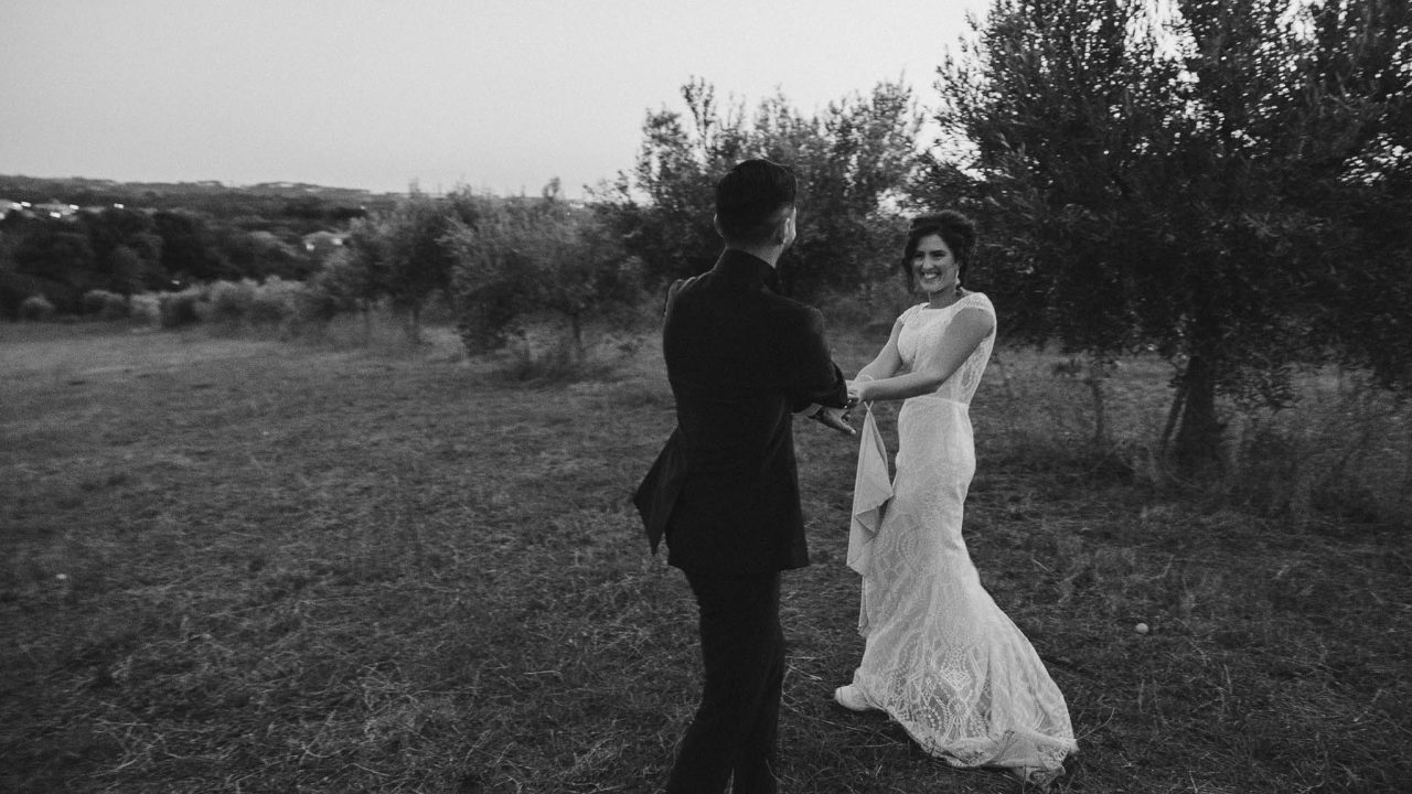 Paolo e Silvia Coppia di sposi che si tengono per mano e sorridono durante un momento spontaneo in campagna al tramonto – fotografia di matrimonio in stile reportage