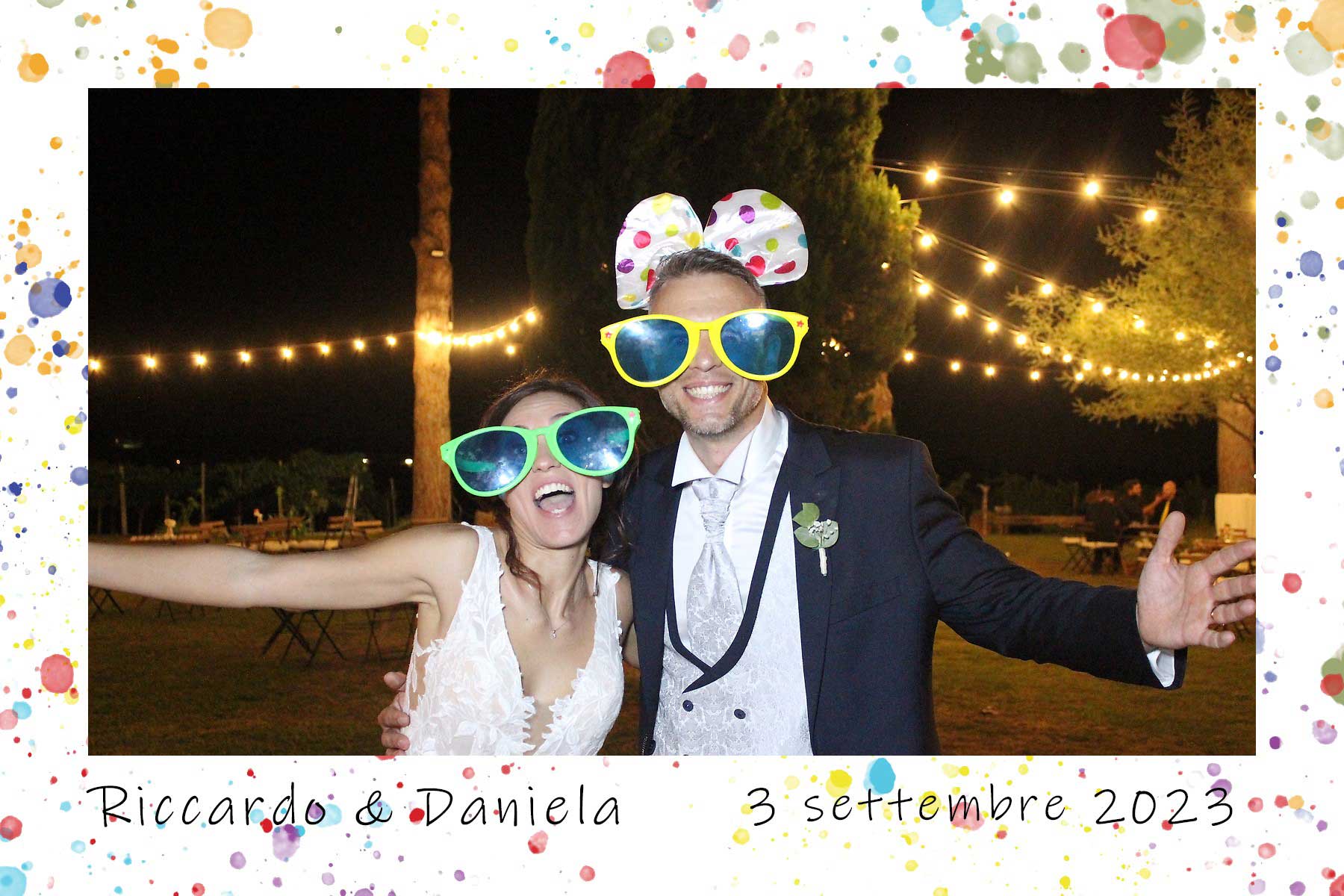 Photo booth matrimonio Riccardo e Daniela – Fatti un Selfie by Max Giubilei Sposi divertiti con occhiali e accessori colorati al photo booth Fatti un Selfie durante un matrimonio serale